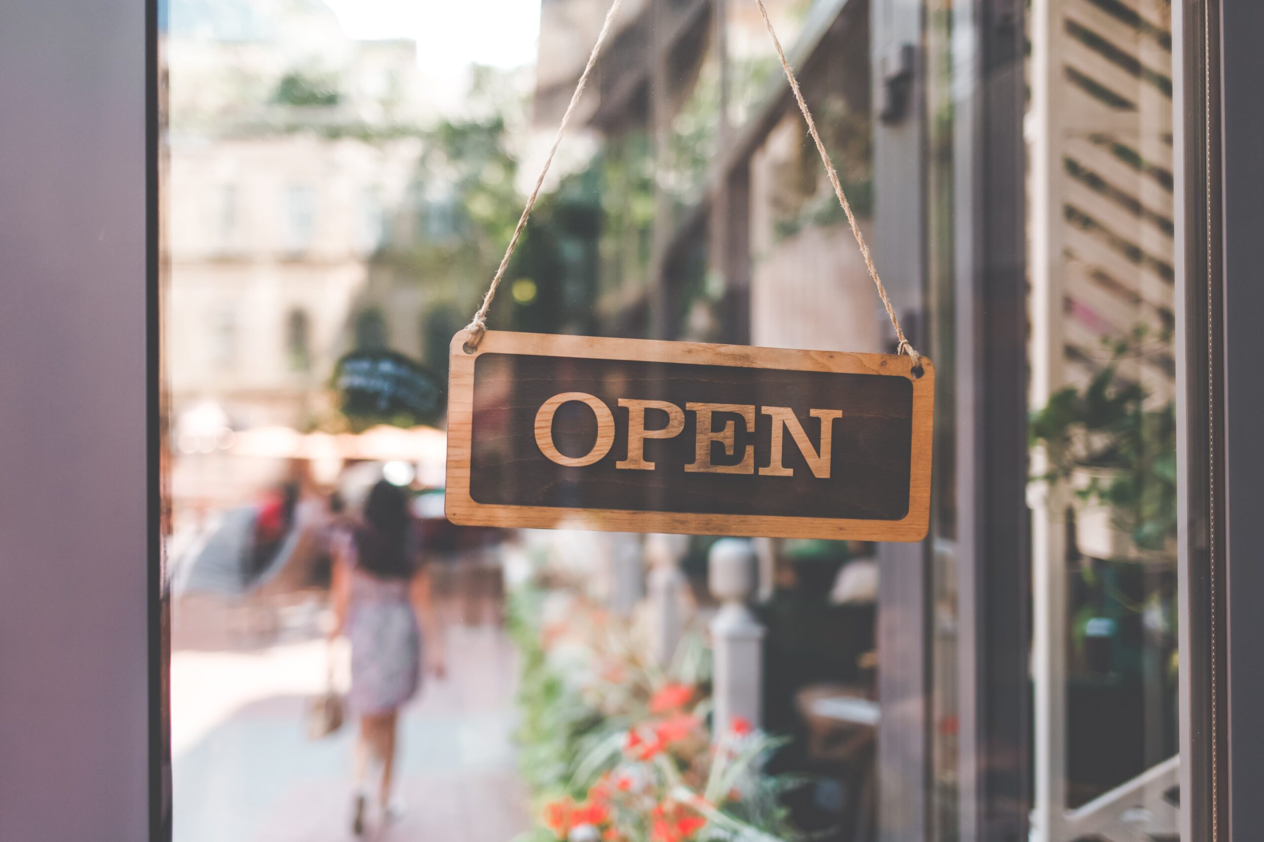 An open sign hanging on a glass door