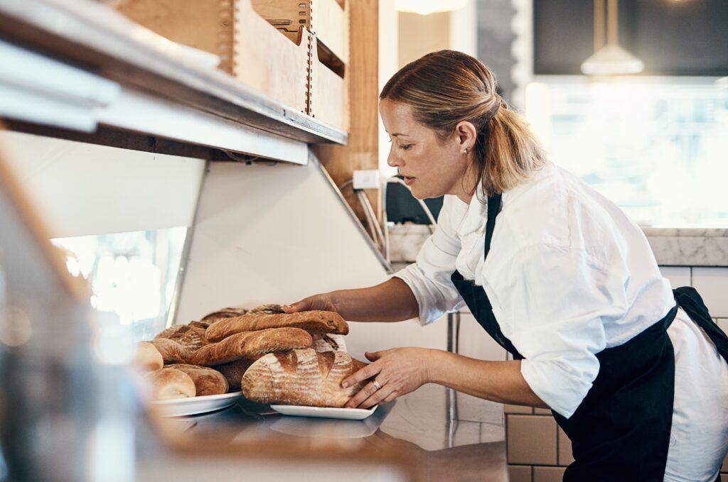 A woman working in a kitchen placing bread on a plate.